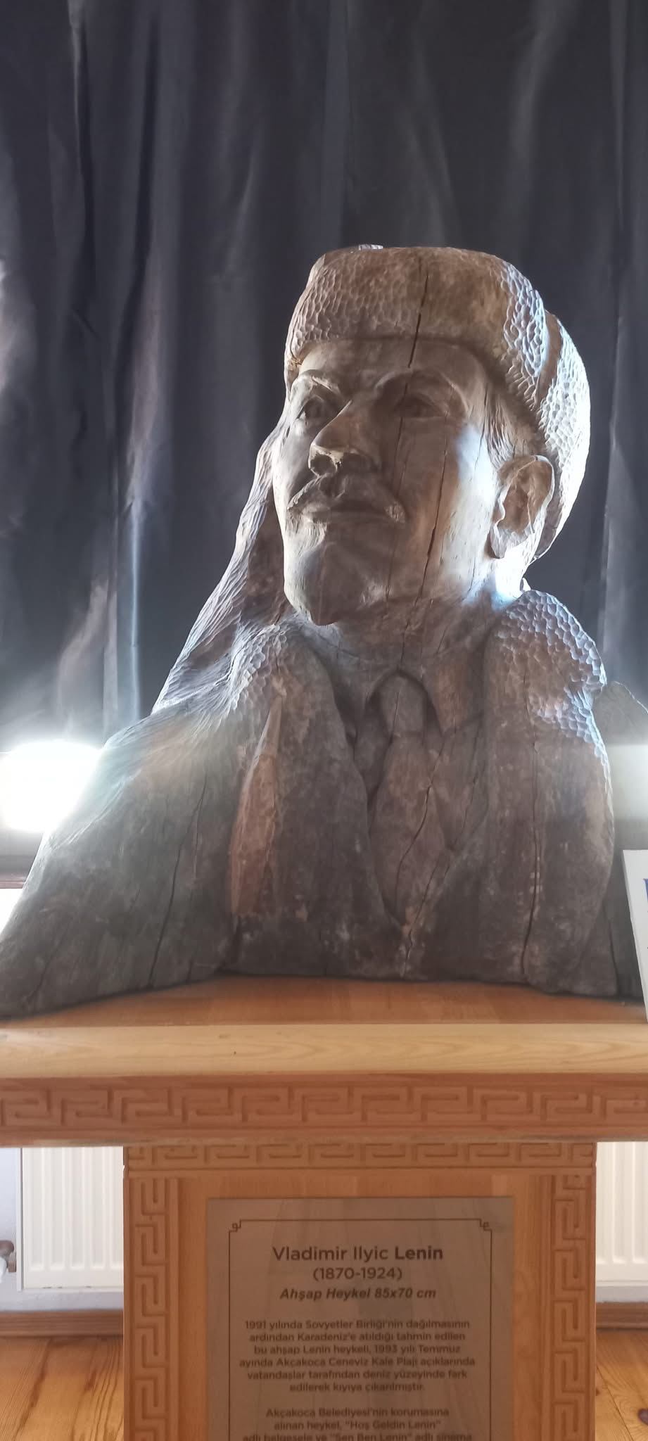 The wooden Lenin bust and its information panel on display at the Bekir Özkök Culture House